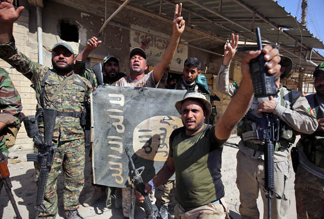 Fighters of Hashed Al Shaabi (Popular Mobilisation Units) flash the victory gesture as they hold upside down a banner bearing the logo of the Daesh group, during the advance in the town of Tal Afar, west of Mosul, after the Iraqi government announced the launch of the operation to retake it from Daesh control on Saturday (AFP photo)