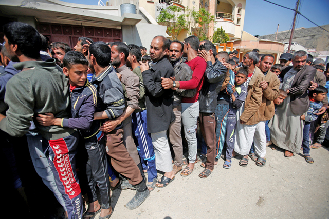 Displaced Iraqi people who fled their homes stand in a queue to receive aid in the city of Mosul, Iraq, on Sunday (Reuters photo)