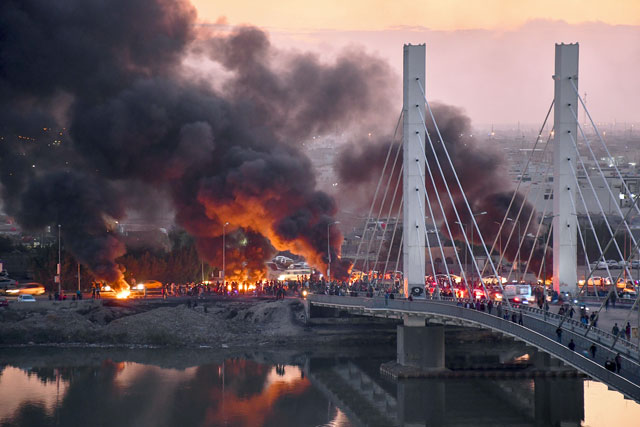 Iraqi anti-government demonstrators block a bridge with debris and burning tyres in the southern Iraqi city of Nasiriyah on Sunday (AFP photo)