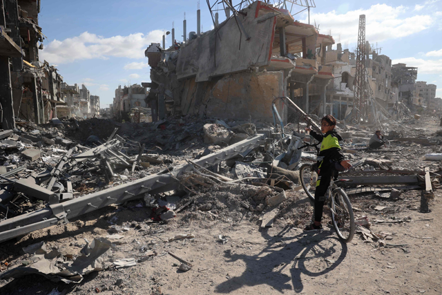 A Palestinian youth on a bicycle gestures in front of a ruined neighbourhood of Gaza's southern city of Rafah on January 20, 2025, as residents return following a ceasefire deal a day earlier between Israel and Hamas (AFP photo)