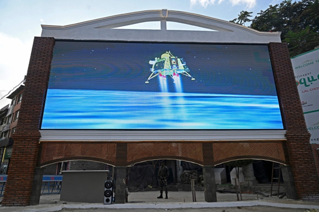 An Indian paramilitary trooper stands guard as a live telecast is aired near a clock tower in Srinagar on August 23, showing the Chandrayaan-3 spacecraft minutes before its successful lunar landing on the south pole of the Moon (AFP photo)