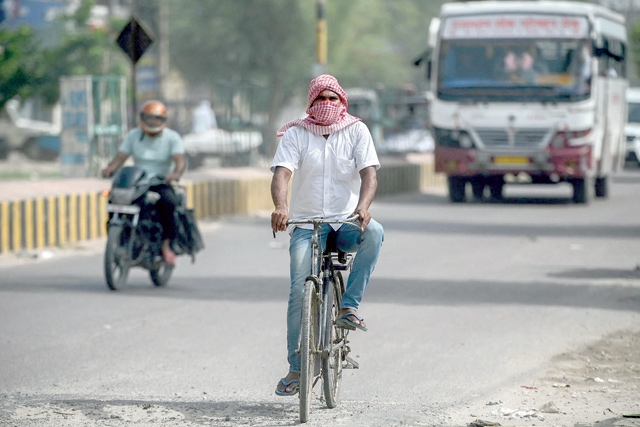 In this file photo taken on July 4, a cyclist covers his face with a cloth to shield from the scorching sun as he peddles along a road on a hot summer afternoon in Sri Ganganagar in the northern Indian state of Rajasthan (AFP photo)