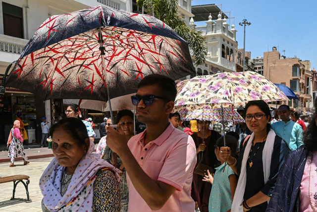 Tourists walk with umbrellas to protect themselves from the sun, on a hot summer day during heatwave in Amritsar on Monday (AFP photo)