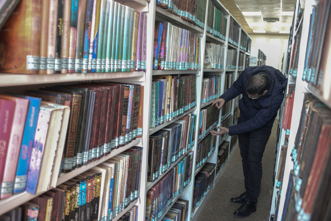 A librarian picks a book from the library collection of the University of Iraq’s northern city of Mosul, on January 31  (AFP photo)