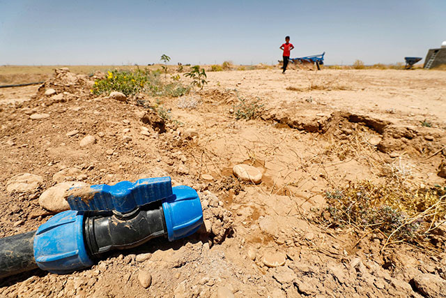 A boy walks through a dried up agricultural field near a dry water hose in the Saadiya area, north of Diyala in eastern Iraq on June 24 (AFP photo)