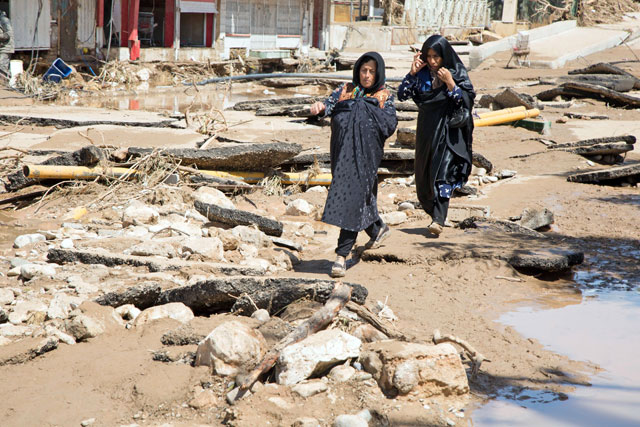 An Iranian woman walks through a flooded street in the city of Poldokhtar in the Lorestan province, on Tuesday (AFP photo)