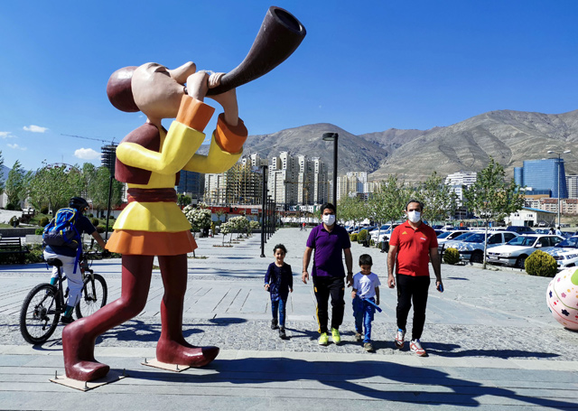 People wearing protective masks amid the coronavirus pandemic accompany children out next to Chitgar Lake in Iran's capital Tehran on Monday (AFP photo)