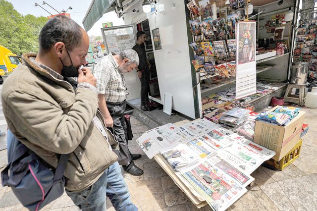 Men view the covers of local newspapers laid out at a stall in the Shemiran district of Iran's capital Tehran on Wednesday (AFP photo)