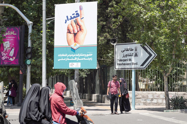 Iranians ride on a motorcycle past an electoral poster in the capital Tehran on Saturday (AFP photo)