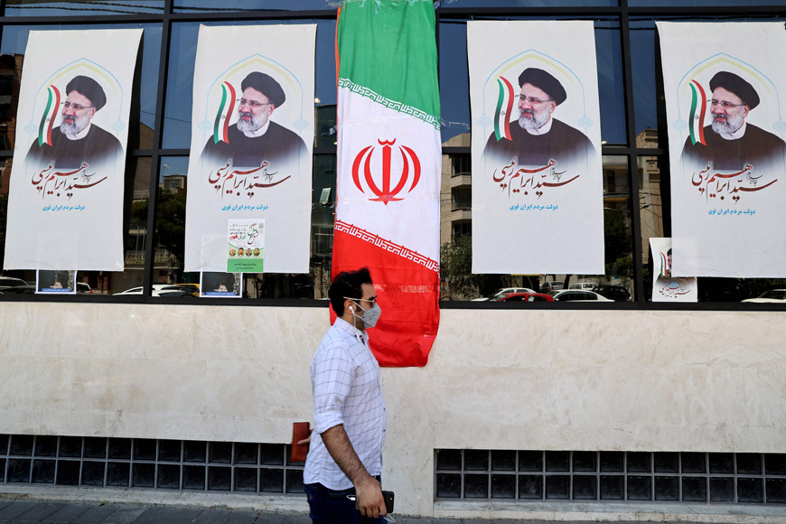 An Iranian man walks by posters of presidential candidate Ebrahim Raisi outside a campaign office in Tehran, on Monday  (AFP photo)