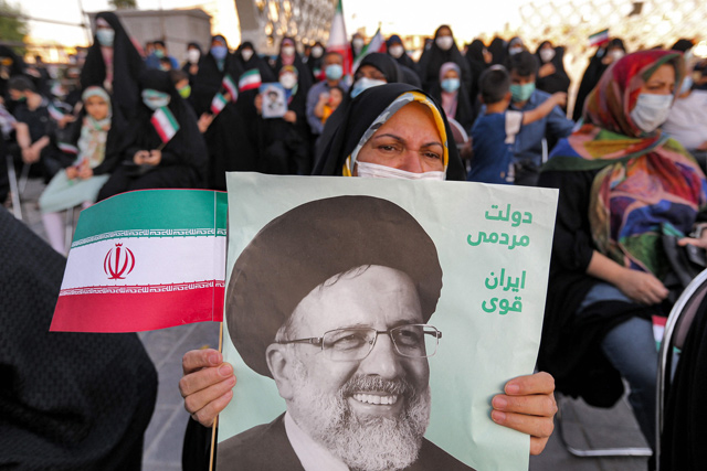 A woman holds a poster of Iran’s newly-elected president Ebrahim Raisi, with text in Persian reading ‘Government of the people, strong Iran’, as supporters celebrate his victory in Imam Hussein square in the capital Tehran, on Saturday (AFP photo)