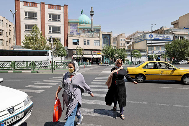 Iranian women cross a street in downtown Tehran on Tuesday, as authorities tighten restrictions amid the COVID-19 pandemic (AFP photo)