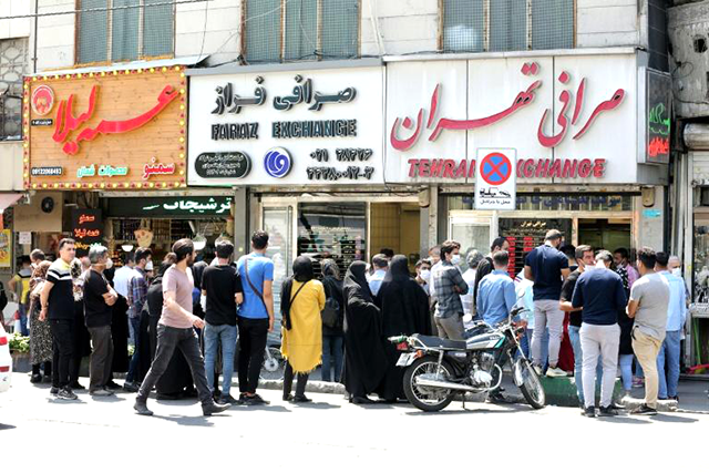 Iranians, wearing protective masks without observing social distancing, queue outside a money exchange office in the capital Tehran (AFP photo)