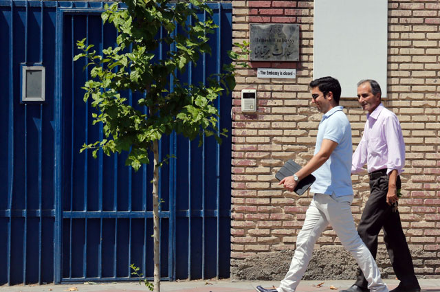 In this file photo taken on August 21, 2015, Iranian men walk past the then closed British embassy in the capital Tehran  (AFP photo)