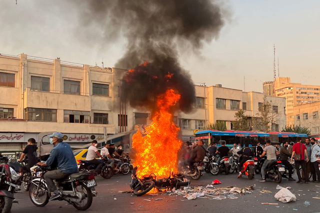A photo obtained by AFP outside Iran shows people gathering next to a burning motorcycle in the capital Tehran on Saturday  (AFP photo)