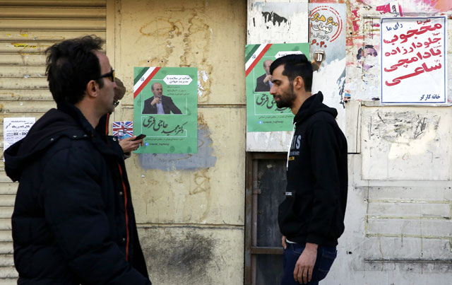 Iranians walk past an electoral poster of a candidate in the upcoming parliamentary elections on a street in Tehran on Wednesday (AFP photo)