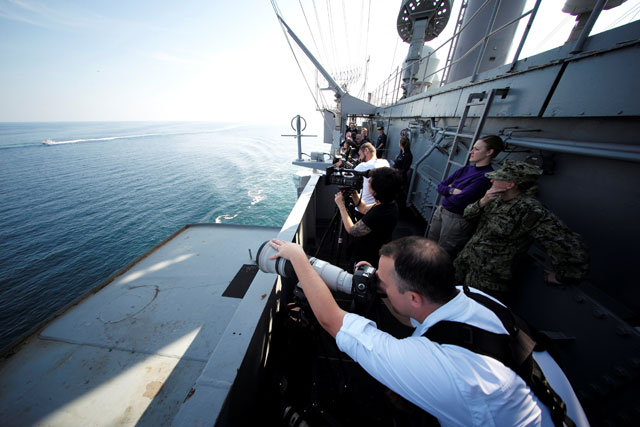 Members of the media aboard the USS John C. Stennis take photos of Iranian Revolutionary Guard patrol boat making its way to the Gulf through the Strait of Hormuz on Friday (Reuters photo)