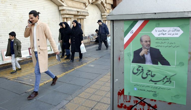 Iranians walk past an electoral poster of a candidate of the upcoming parliamentary elections on a street in Tehran on February 12, Iranian candidates for the parliamentary elections allowed to begin campaigns from Thursday for elections scheduled on February 21, 2020  (AFP photo)