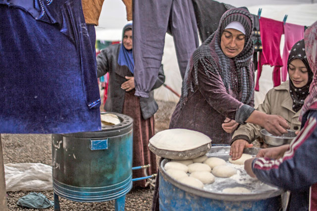 Iraqi displaced women cook bread in Khazer camp for the displaced Iraqi Kurdistan, Iraq, on Saturday (AP photo)