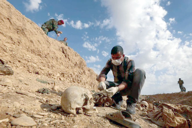 An Iraqi man inspecting the remains of Yazidi who were killed by Daesh terror group, that were discovered in a mass grave, on February 3, 2015 (AFP photo)