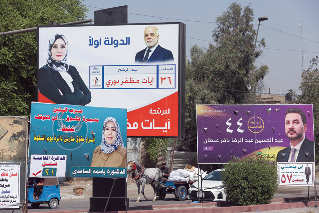 Iraqis drive past electoral billboards and placards of candidates for the upcoming parliamentary elections, in the capital Baghdad, on Monday (AFP photo)