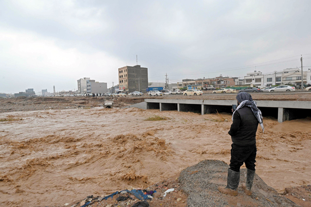 A resident takes a video of the water levels of a river on the outskirts of Erbil, the capital of the northern Iraqi Kurdish autonomous region, on Friday (AFP photo)