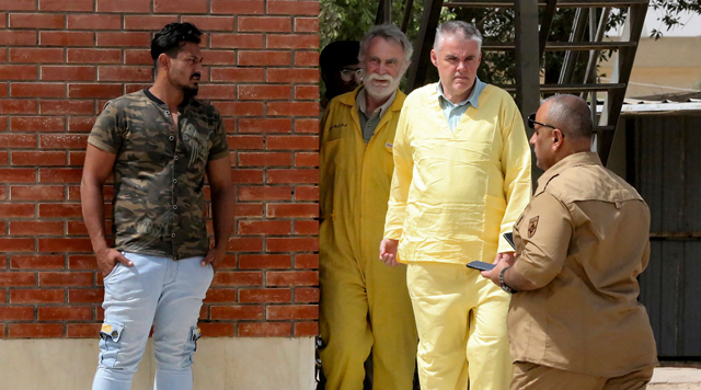 James Fitton, 66, a retired British geologist (left) and Volker Waldmann, 60, a Berlin psychologist, are dressed in the yellow uniform of detainees as they are arrive at a courthouse in the Iraqi capital Baghdad on Sunday, where they are being tried over ancient pottery shards, considered by the Iraqi authorities as antiquities, found in their luggage at the airport  (AFP photo)