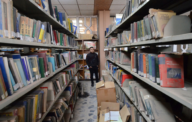 A man stands amidst dusty books in the new library of Mosul University, in Iraq’s northern city of Mosul, on April 17  (AFP photo)