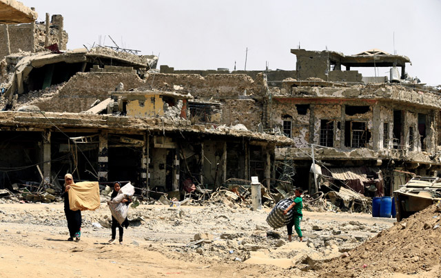 Civilians carry their belongings as they walk between destroyed buildings by clashes in the Old City of Mosul, Iraq, on Sunday (Reuters photo)
