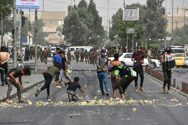 Iraqi protesters hurl stones at security forces amid clashes at an anti-government demonstration in the southern city of Nasiriyah (AFP photo)