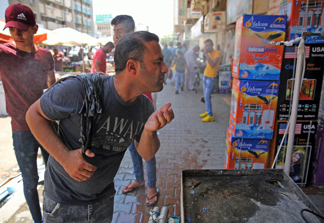 An Iraqi man uses a curbside shower to cool off during a heat wave in the capital Baghdad on Friday (AFP photo)