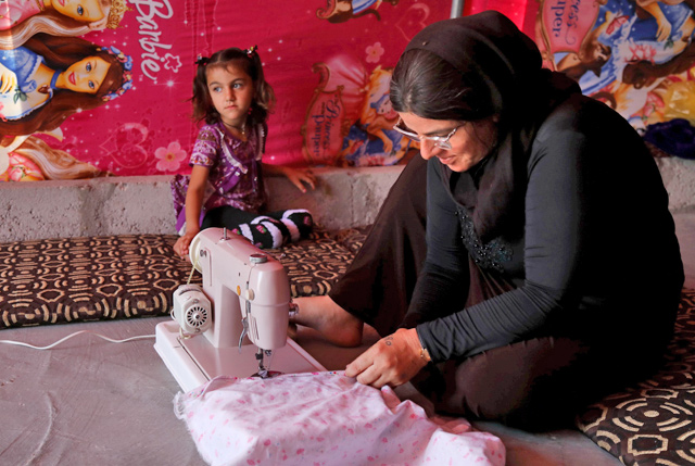 Iraq’s Yazidi survivor Layleh Shemmo sews inside her tent in the Khonke camp for displaced persons in northwestern Iraq on June 24  (AFP photo)