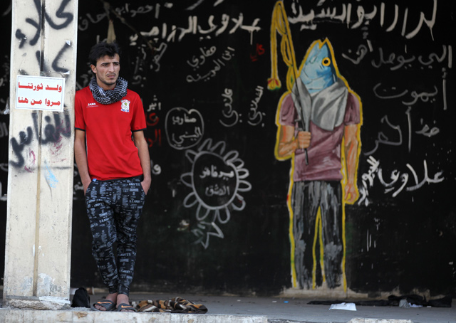 An Iraqi demonstrator stands in front of a mural inspired by ongoing anti-government protests, in Tahrir Square in the capital Baghdad, on Thursday (AFP photo)