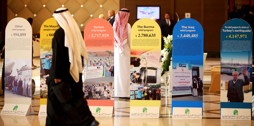 Participants walk past brochures of previous funds collected by the International Islamic Relief Organisation (IIRO), during the Kuwait International Conference for Reconstruction of Iraq on Monday, in Kuwait City (AFP photo)
