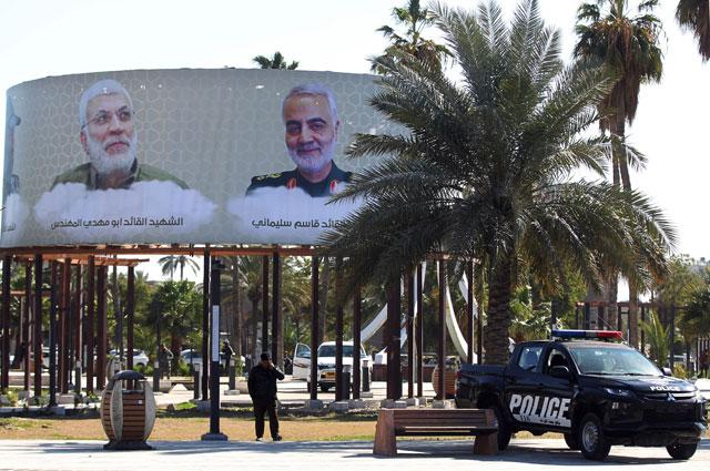 This photo taken on Sunday in the Iraqi capital Baghdad's district of Karrada shows an Iraqi police vehicle parked beneath mourning billboards on display, depicting top Iranian general Qassem Soleimani and Iraqi paramilitary commander Abu Mahdi Al Muhandis (AFP photo)