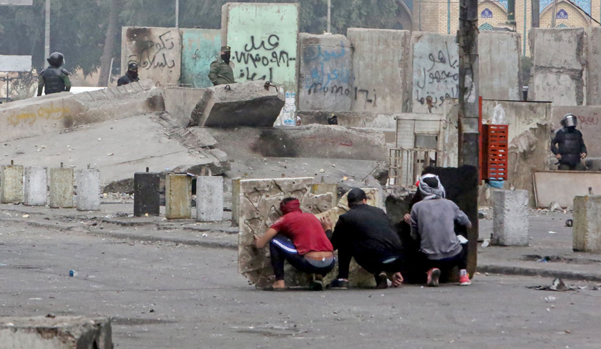 Iraqi protesters take cover amid clashes with security forces at Al Khilani Square in the capital Baghdad on Sunday during ongoing anti-government demonstrations  (AFP photo)