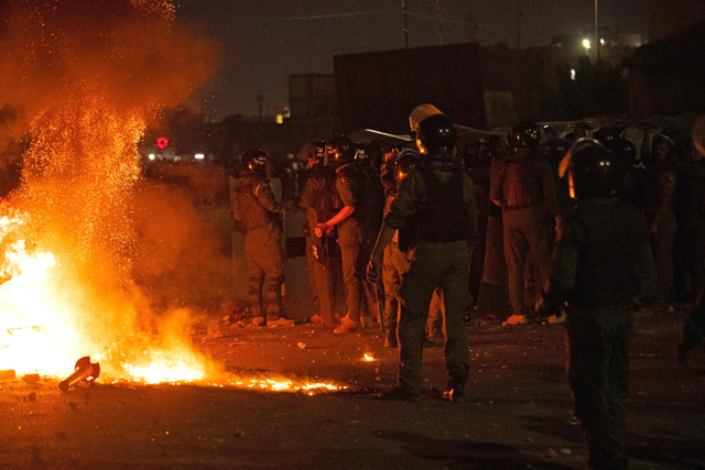 Members of Iraqi security deploy near burning tyres amid clashes with protesters during a rally to mark three years since nationwide demonstrations erupted against endemic corruption, in the southern city of Basra, on Saturday (AFP photo)