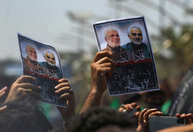 Mourners hold images of Iranian general Qasem Soleimani and senior Iraqi military commander Abu Mahdi Al Muhandis after they were killed in a US drone strike — both men began their military careers in the Iran-Iraq war (AFP photo)