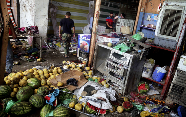 Citizens inspect the scene after a bomb explosion at outdoor market in Baghdad’s northern neighbourhood of Shaab, Iraq, on Tuesday (AP photo)