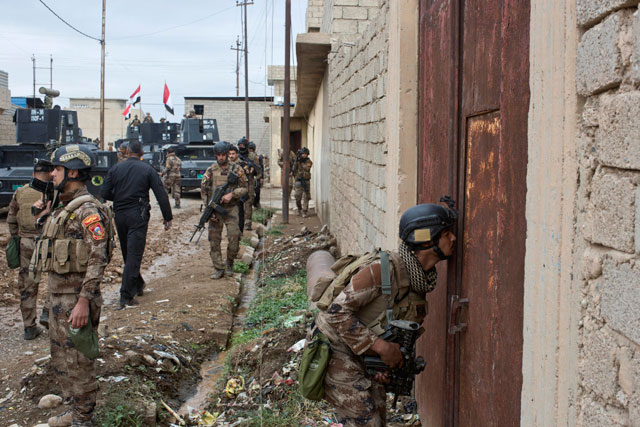 An Iraqi special forces soldier peeks through a hole in a door as his unit gets ready to search a compound in Gogjali, an eastern district of Mosul, Iraq, on Wednesday (AP photo)