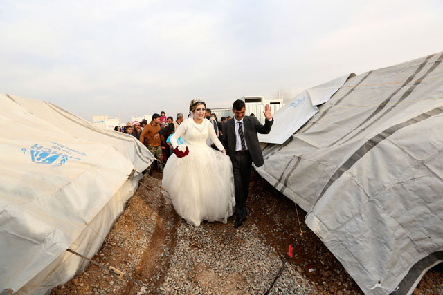 Iraqi internally displaced groom Jassim Mohammed walks with his bride, Amena Ali, during their wedding ceremony at a camp for internally displaced people in Khazir, near Mosul, Iraq, Thursday (AP photo)