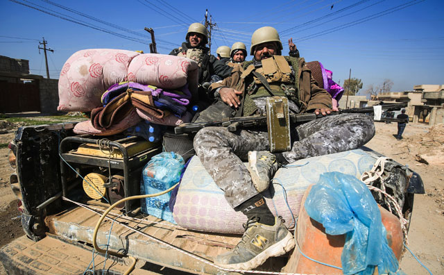Members of the Iraqi security forces pose from atop an armoured vehicle in the village of Al Buseif, south of Mosul, during an offensive to retake the western side of the city from Daesh extremists on Wednesday (AFP photo)