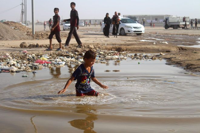 A displaced Iraqi boy from the Fallujah area plays in a puddle of water at a camp near Amiriyah Al Fallujah, on Wednesday (AFP photo)