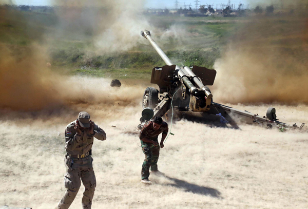 Members of the Popular Mobilisation Units, pro-government paramilitary forces, cover their ears as they fire a multiple rocket launcher during clashes with Daesh militants in Iraq's northern Kirkuk province on Thursday (AFP photo)
