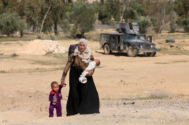 In this file photo, a mother and her children flee their homes during clashes between Iraqi security forces and Daesh militants in Hit, 140 kilometres west of Baghdad, Iraq. Families, many with small children and elderly relatives, say they walked for hours Monday through desert, littered with roadside bombs to escape air strikes and clashes (AP photo)