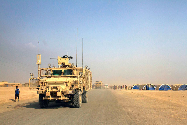 A convoy of armoured coalition vehicles passes through a camp for displaced civilians on the road outside Qayyarah Air Base, south of Mosul, on Tuesday (AP photo)
