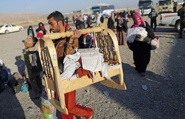 Displaced Iraqi families who fled Mosul due to the ongoing fighting between Iraqi forces and Daesh militants wait to be taken to a camp for displaced people on Tuesday in Bartalla, east of Mosul (AFP photo)
