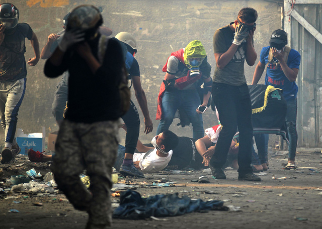 Iraqi protesters react to tear gas amid clashes with security forces at Baghdad's Khallani Square during ongoing anti-government demonstrations on Tuesday (AFP photo)