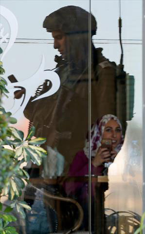 The reflection of a member of Israeli forces is seen at the window of a restaurant during a raid in the West Bank city of Ramallah on Monday (AFP photo)