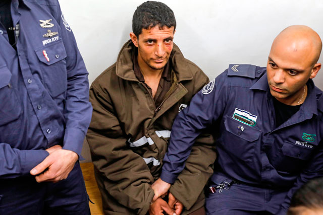 Arafat Irfaiya (centre), a 29-year-old Palestinian suspected of killing a young Israeli woman, is seen in Israeli custody at the magistrate's court in occupied Jerusalem, on Monday (AFP photo)